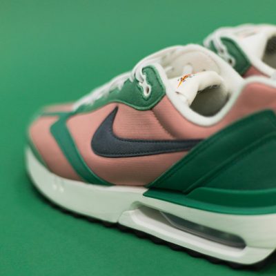 Close-up of trendy pink and green sneakers with a visible air cushion on a green background.